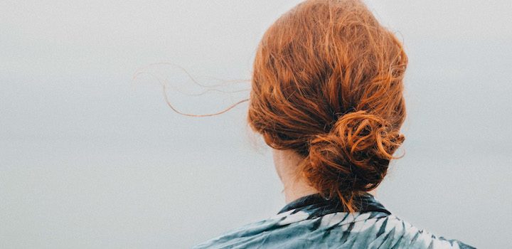 a readhead woman looking at the sea and missing her home