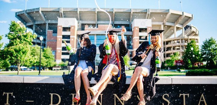 3 female students celebrating graduation from university and popping champagne