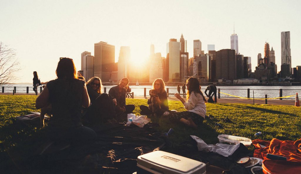 group of students sitting on the river bank in park and talking