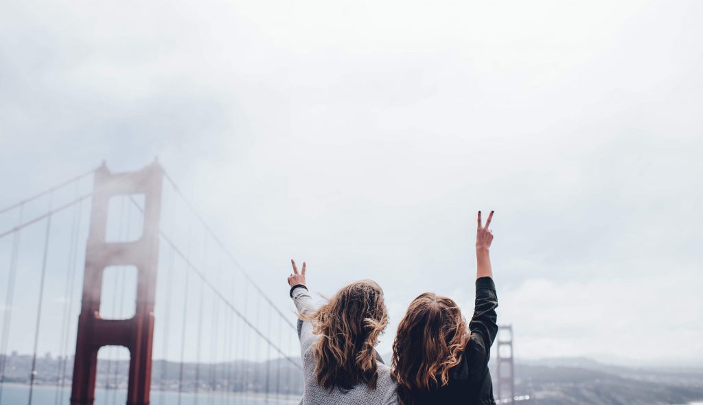 2 students making a photo of themselves in front of a big bridge in a foggy weather